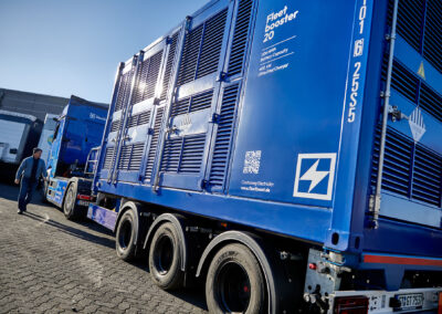 Mobiler Energiecontainer von FleetBoost auf einem Trailer hinter einem Elektro-Lkw, abgebildet auf einem Betriebsgelände und ausgelegt für flexible Stromversorgung und Ladeinfrastruktur.