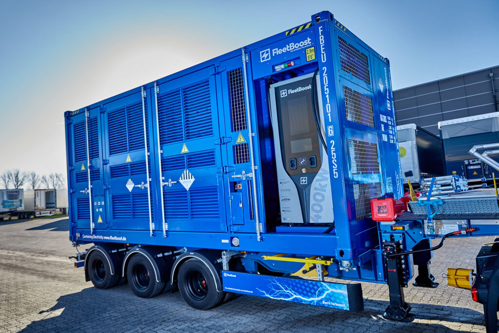 Contenedor de energía móvil de FleetBoost en un remolque con unidad de carga integrada, instalado en un recinto logístico para proporcionar un suministro eléctrico flexible y una infraestructura de carga.
